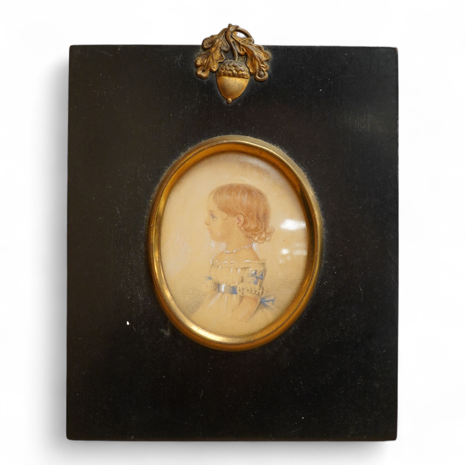Regency School, Oval portrait miniature of a young girl in profile, watercolour on card, housed in an ebonised and gilt frame, overall 12 x 10cm